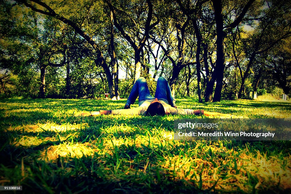 Woman lying in the grass surrounded by trees