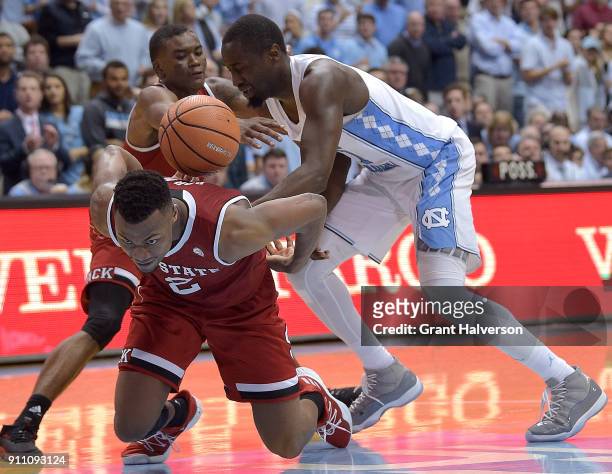 Torin Dorn and Markell Johnson of the North Carolina State Wolfpack battle Theo Pinson of the North Carolina Tar Heels for the ball during their game...