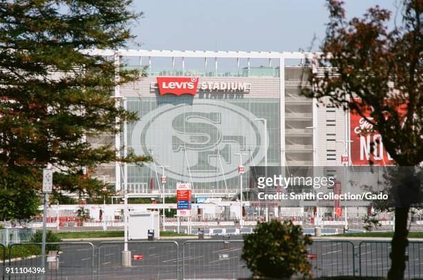 Side view of Levi's Stadium, home of the San Francisco 49ers football team, viewed through trees across a parking lot, in the Silicon Valley, Santa...