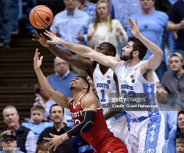 Allerik Freeman of the North Carolina State Wolfpack shoots against Theo Pinson and Luke Maye of the North Carolina Tar Heels during their game at...
