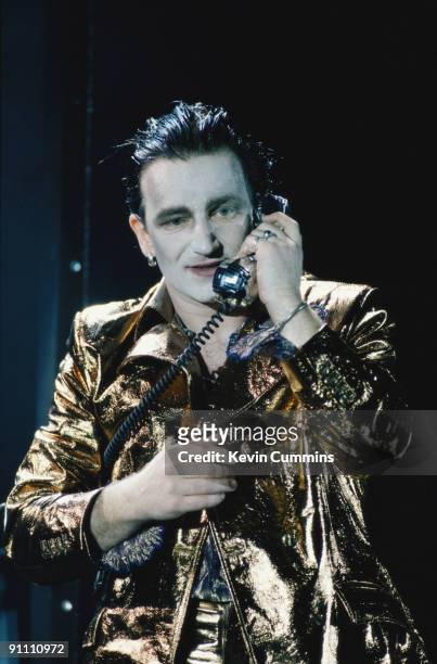 Singer Bono makes a phone call, in his stage persona of Mr. MacPhisto, during a concert by Irish rock group U2 on their 'Zoo TV' tour, 1992.