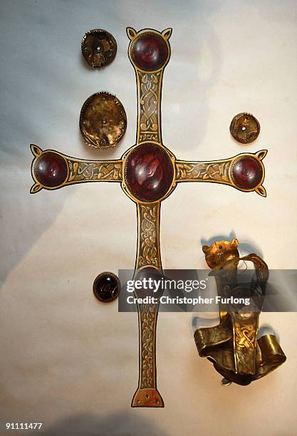 Mangled gold cross sits nexts to an artists impression of how it would have originally looked, as part of the The Staffordshire Hoard, the UK's...