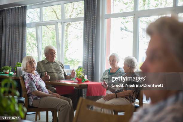 senior men and women discussing at nursing home - 80s living room fotografías e imágenes de stock