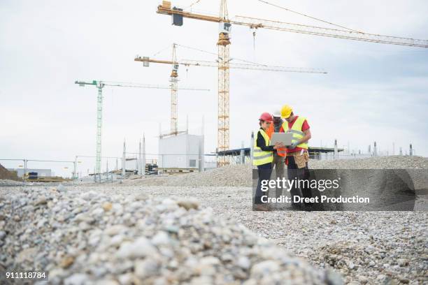 female architect and construction workers using laptop at site - african creative with laptop working outside stock-fotos und bilder