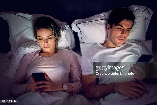handy - sucht paar sms und surfen im bett - couple on bed stock-fotos und bilder