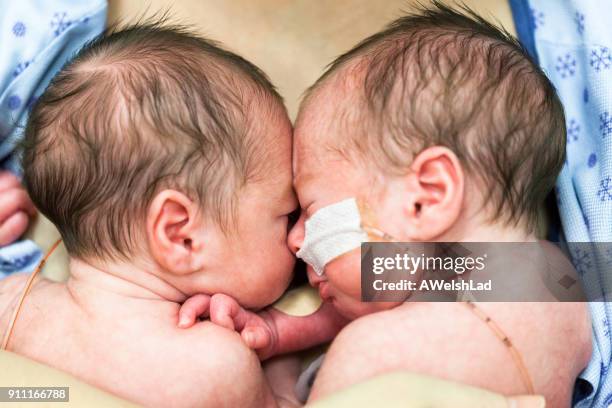 相同的雙胞胎男孩睡在他們的母親的乳房並排 - premature 個照片及圖片檔