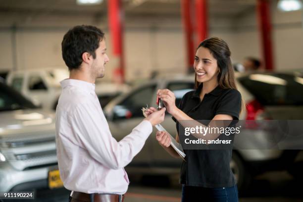 weibliche mechaniker geben autoschlüssel zu einem glücklichen kunden bei einer auto-werkstatt - happy client by broken car stock-fotos und bilder