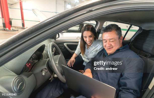 mechaniker mit technologie, um probleme mit dem auto zu einer kundin erklären - happy client by broken car stock-fotos und bilder