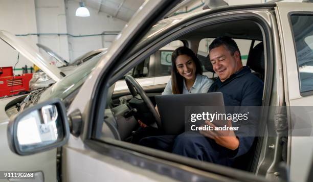 mechaniker im gespräch mit einer kundin in einem auto in einer garage - happy client by broken car stock-fotos und bilder