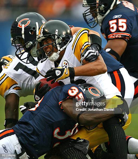 Hines Ward of the Pittsburgh Steelers is tackled by Zackary Bowman of the Chicago Bears as teammate Hunter Hillenmeyer pushes Santonio Holmes away on...