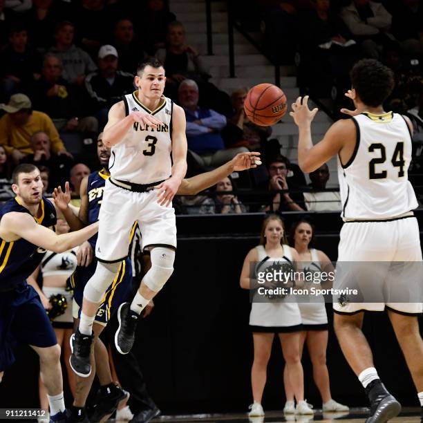 The game's leading scorer Fletcher Magee guard Wofford College Terriers turns in mid-air to pass the basketball against the East Tennessee State...