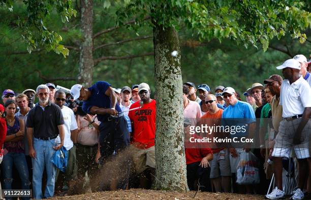 Tiger Woods plays his second shot from the rough on the eighth hole during the first round of THE TOUR Championship presented by Coca-Cola, the final...