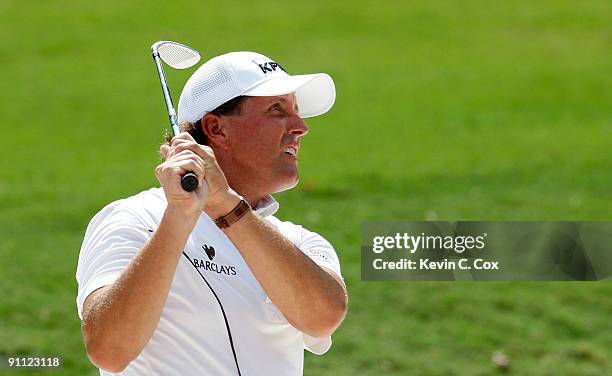 Phil Mickelson chips out of the sand trap onto the eighth green during the first round of THE TOUR Championship presented by Coca-Cola, the final...