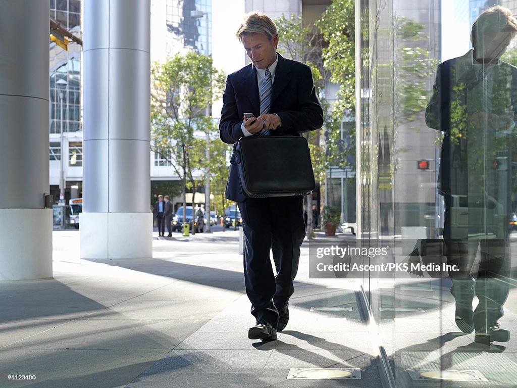 Businessman checks text message, downtown corridor