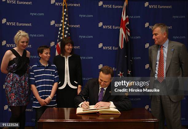 New Zealand's Prime MInister John Key signs the New York Stock Exchange's guest book as his daughter Stephie Key , son Max Key and wife Bronah Key...