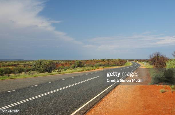 looking west down lasseter highway that leads to uluru, petermann, northern territory, australia - uluru road stock-fotos und bilder