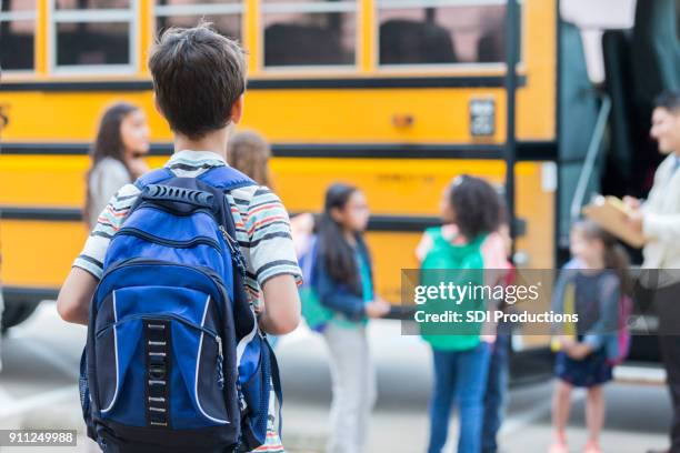 ung pojke väntar att ladda skolbuss - first day of school bildbanksfoton och bilder
