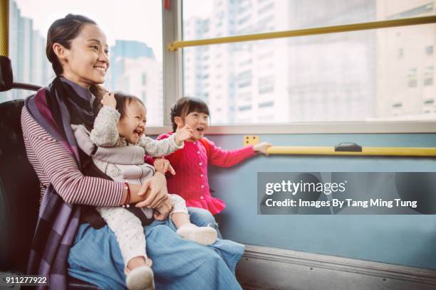 pretty young mom, her lovely baby and daughter riding on a bus joyfully. - kids sitting together in bus stock pictures, royalty-free photos & images