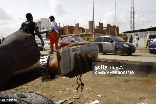 Picture taken on February 19, 2015 shows an Angolan money changer holding a bundle of Angolan Local currency banknotes in a street in Luanda, Angola....