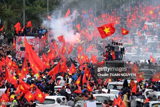 Large crowd of football fans wave the national flag as they follow a bus carrying the members of the U-23 Vietnamese National team through the...