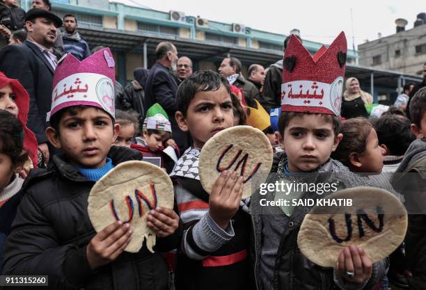 Palestinian children hold bread patties during a protest against aid cuts, outside the United Nations' offices in Khan Yunis in the southern Gaza...