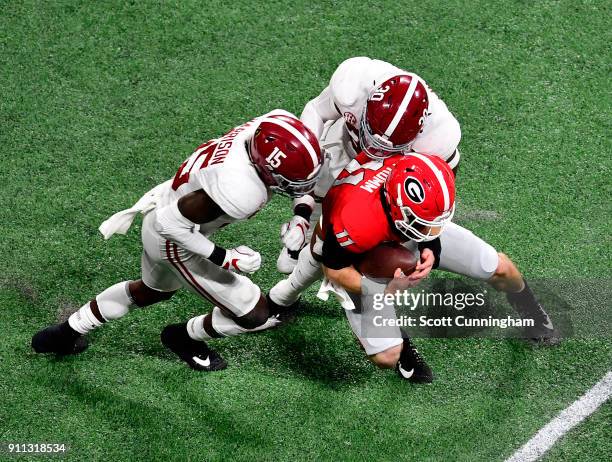 Jake Fromm of the Georgia Bulldogs is tackled by Ronnie Harrison and Mack Wilson of the Alabama Crimson Tide in the CFP National Championship...