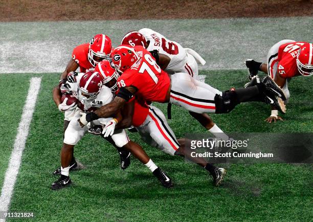 Damien Harris of the Alabama Crimson Tide is tackled by Roquon Smith, J. R. Reed, and D'Marcus Hayes of the Georgia Bulldogs in the CFP National...