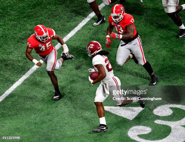 Najee Harris of the Alabama Crimson Tide carries the ball against Reggie Carter and Jonathan Ledbetter of the Georgia Bulldogs in the CFP National...