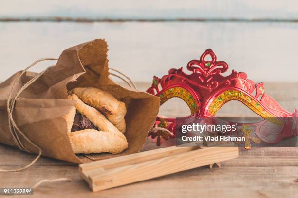 purim jewish holiday composition with hamantaschen, purim mask and purim gragger on a vintage wood background with copy space"r"n - purim stock pictures, royalty-free photos & images