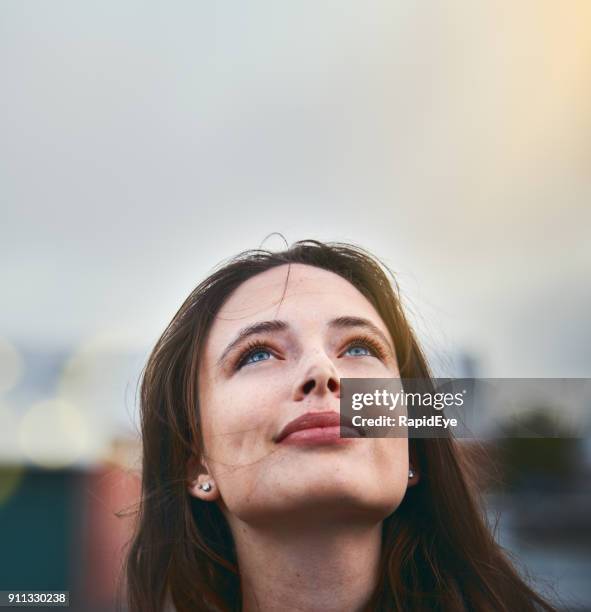 jonge vrouw kijkt hoopvol als ze haar ogen naar de hemel roept - inzicht stockfoto's en -beelden