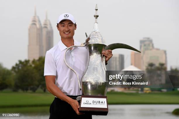 Haotong Li of China celebrates victory with the trophy after the final round on day four of the Omega Dubai Desert Classic at Emirates Golf Club on...