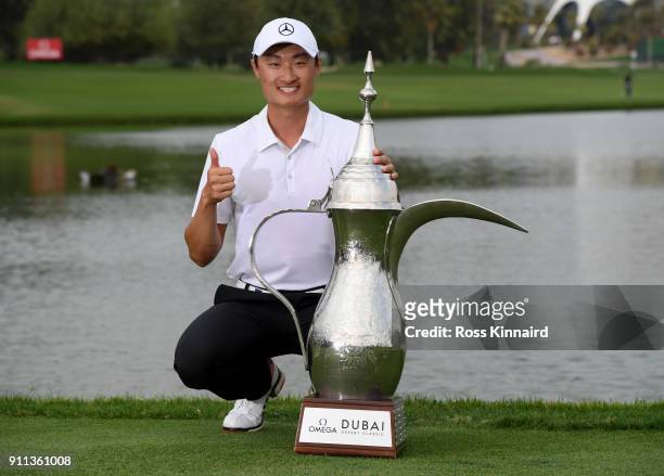Haotong Li of China celebrates victory with the trophy after the final round on day four of the Omega Dubai Desert Classic at Emirates Golf Club on...