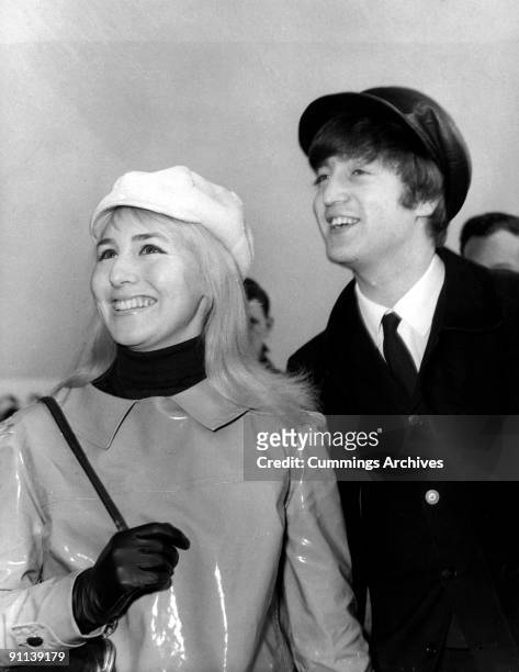 Photo of John LENNON and Cynthia LENNON; while in The Beatles, posed with his wife Cynthia at Heathrow Airport