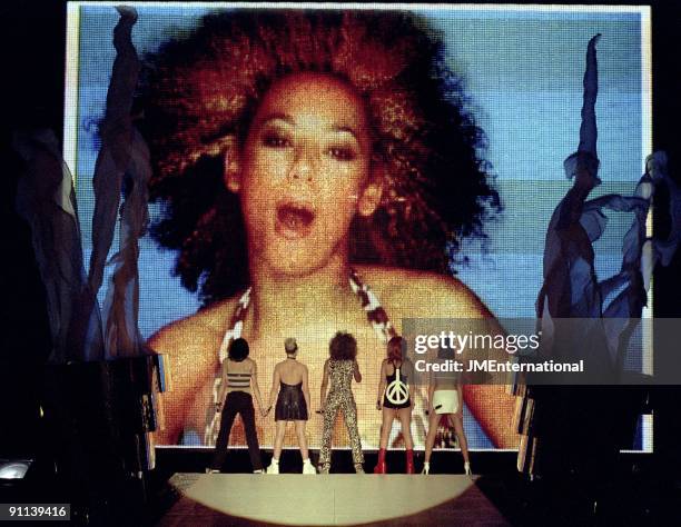 Photo of SPICE GIRLS, Group performing live on stage, giant screen L-R Melanie Chisholm , Emma Bunton, Melanie Brown , Geri Halliwell and Victoria...