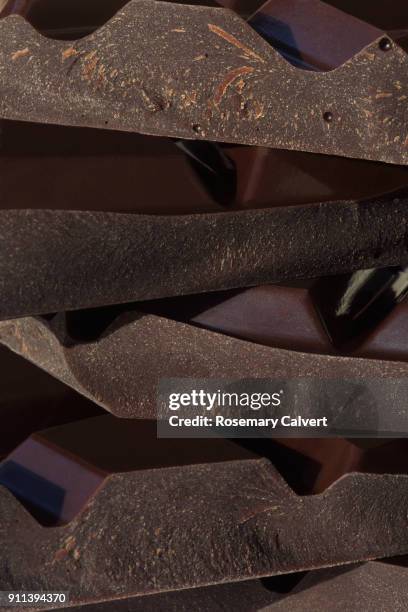 close-up of broken pieces of dark chocolate in stack. - dark chocolate stock pictures, royalty-free photos & images