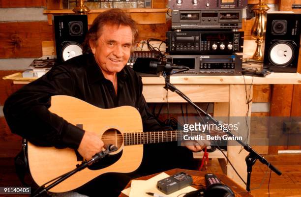 Photo of Johnny CASH, Posed portrait of Johnny Cash, with Takamine acoustic guitar, recording in home studio