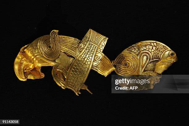 Damaged gold plaque showing two birds of prey gripping a fish between them is displayed at the Staffordshire Hoard exhibition at the Birmingham...