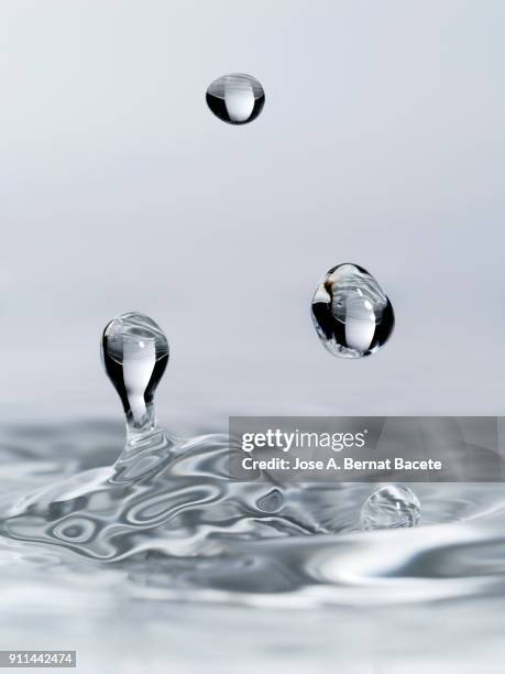 group of drops on line suspended in the air, falling down on a water surface that forms figures and abstract forms, on a white background. - floating on water fotografías e imágenes de stock