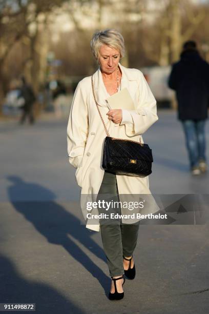 Guest wears a white coat, a Chanel black bag, outside Chanel, during Paris Fashion Week -Haute Couture Spring/Summer 2018, on January 23, 2018 in...