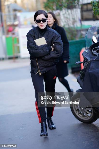 Guest wears sunglasses, a black bomber jacket, sportswear pants, black leather shoes, outside Chanel, during Paris Fashion Week -Haute Couture...