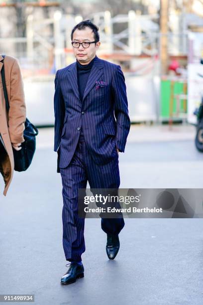 Guest wears glasses, a striped suit, outside Chanel, during Paris Fashion Week -Haute Couture Spring/Summer 2018, on January 23, 2018 in Paris,...