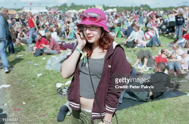 Photo of PP1023_FESTIVALS; Pinkpop, Landgraaf, Nederland, 05 juni 2006, Pop, sfeer, een jong meisje met een roze pinkpophoed op haar hoofd belt met...