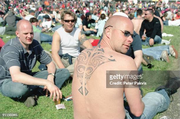 Photo of PP1027_FESTIVALS; Pinkpop, Landgraaf, Nederland, 05 juni 2006, Pop, sfeer, een man met een mooie grote tatto op zijn rug zit omringt door...