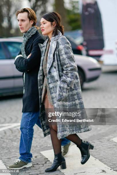 Guest wears a gray checked pattern trench coat, tights, black shoes, outside Chanel, during Paris Fashion Week -Haute Couture Spring/Summer 2018, on...