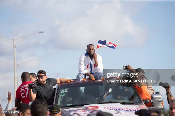 Former Dominican Major League baseball player Vladimir Guerrero holds a Dominican flag as he is driven through the streets after arriving at the Las...