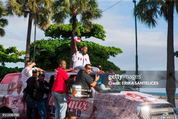 Former Dominican Major League baseball player Vladimir Guerrero holds a Dominican flag as he is driven through the streets after arriving at the Las...
