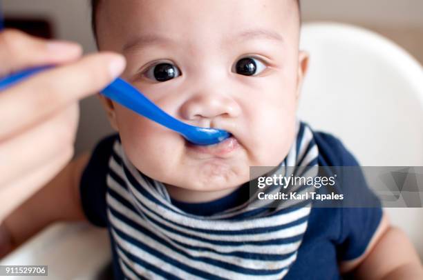 feeding a baby for the first time with solid food - filipino family eating stock-fotos und bilder