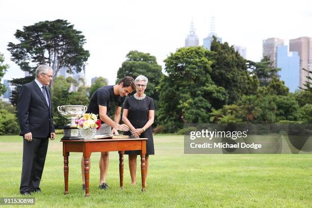 Roger Federer of Switzerland signs the visitors book with the Norman Brookes Challenge Cup alongside Governor Of Victoria, the Honourable Linda...