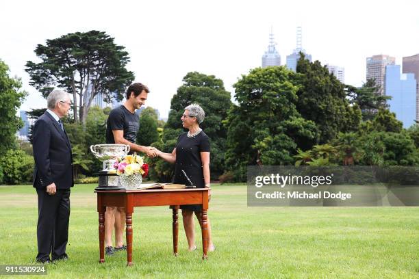 Roger Federer of Switzerland signs the visitors book with the Norman Brookes Challenge Cup alongside Governor Of Victoria, the Honourable Linda...