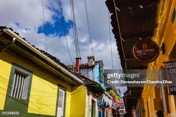 bogotá, kolumbien - suche oben auf der schmalen, alten, bunten calle del embudo: spanischer kolonialarchitektur, terrakotta-fliesen, stromkabel und ein paar von schornsteinen - embudo stock-fotos und bilder